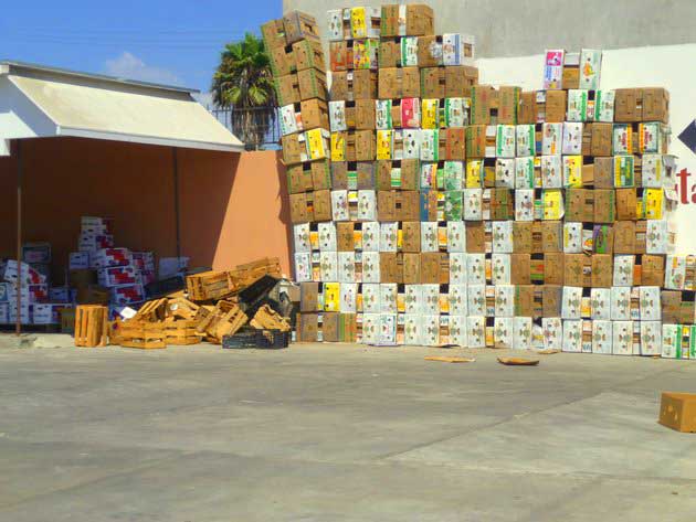 Leaning wall of fruit boxes stacked up in a parking lot at the Los Globos open air markets, in Ensenada, Baja California Norte, Mexico.